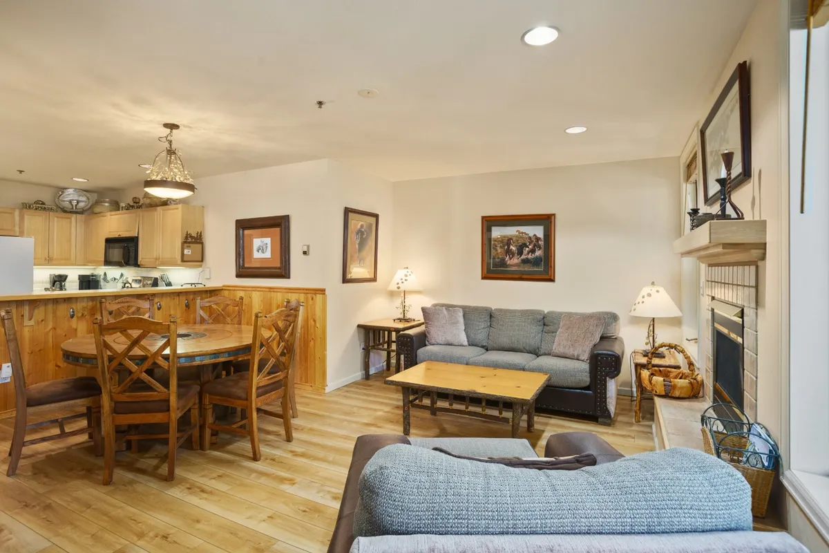 An inviting scene showing a sofa facing a fireplace, a dining table nearby, and tasteful artwork on the walls. The configuration makes it easy to imagine relaxing after a meal, sharing stories, or enjoying a cozy movie night together.