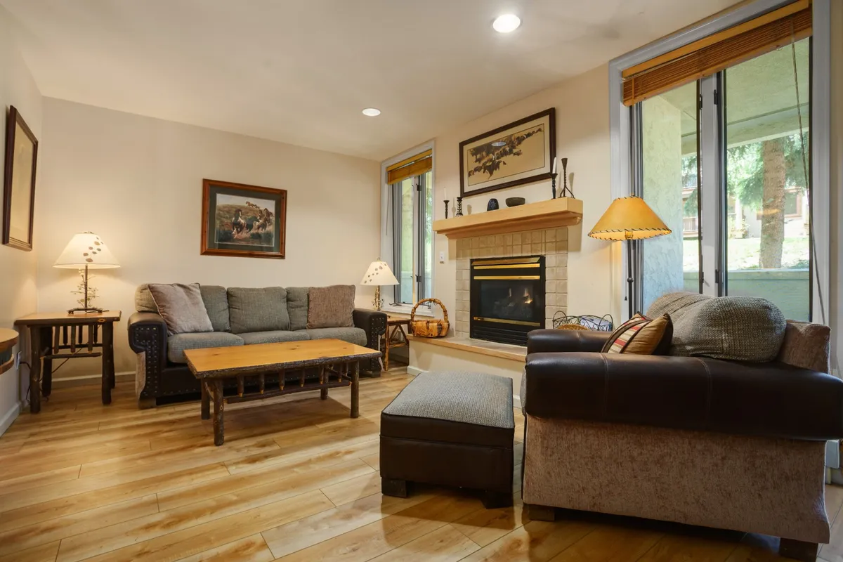 The image showcases a warmly lit living room with a cozy fireplace as the centerpiece, surrounded by a plush sofa seating area, a stylish coffee table, and tasteful wall art. The ambiance invites relaxation, socializing, and family gatherings, capturing the essence of comfort after a day in Steamboat Springs.