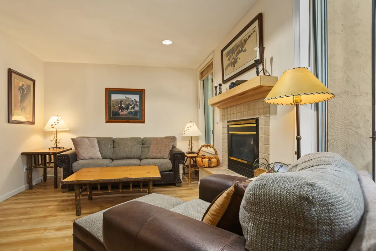 A warm and inviting living room interior with a central fireplace, plush sofa, coffee table, and tasteful artwork. The scene evokes an intimate setting ideal for couples to relax after active days.